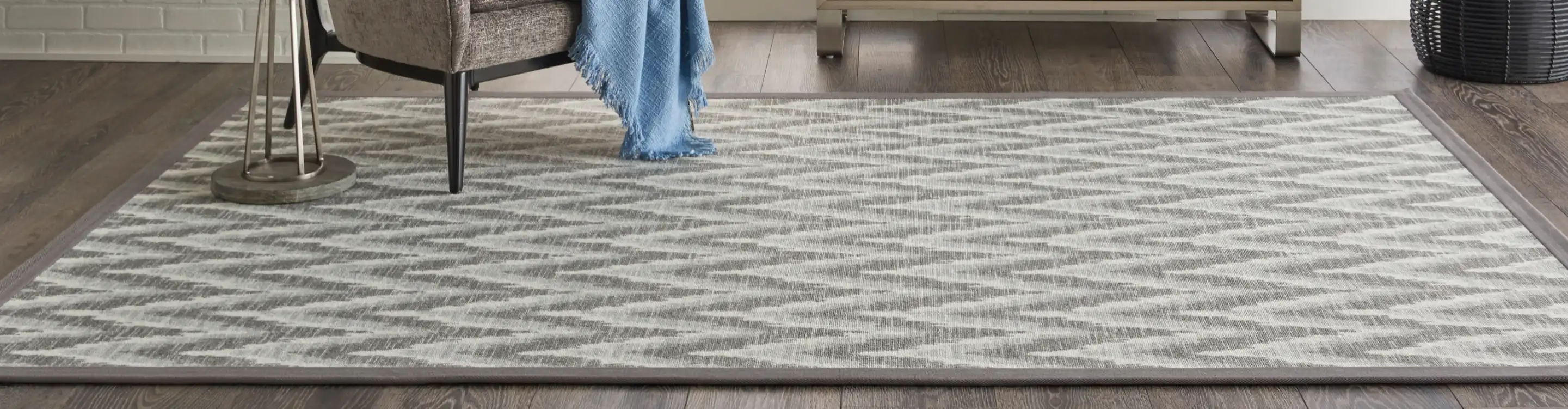 Grey zig zag patterned area rug with chair. 